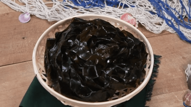 Basket with seaweed and net on wooden table