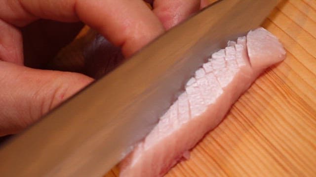 Slicing fresh yellow tail on a wooden board
