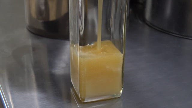 Pouring juice into a Transparent Glass Bottle