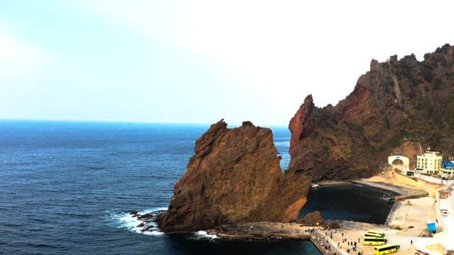 Coastal town with towering rock formations and buses