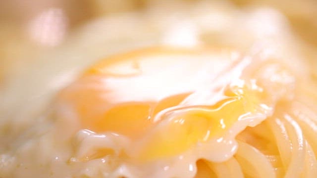 Egg yolk breaking over noodles