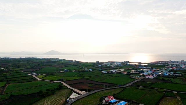 Coastal village with farmland and sunlight over the sea