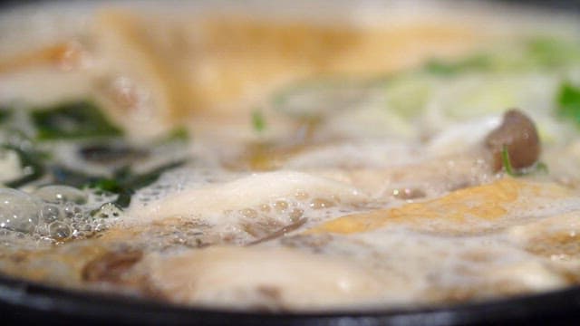 Adding egg to hot soup with mushrooms