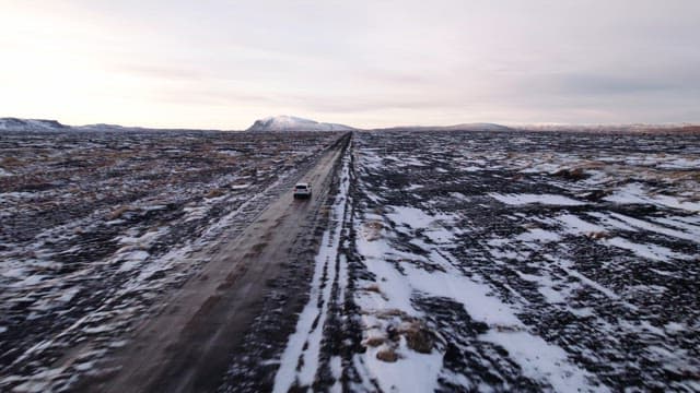Car driving on a snowy road in a vast landscape