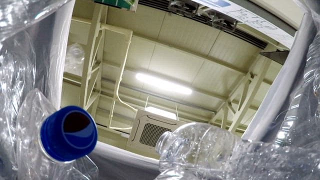 Inside a trash can with falling plastic bottles