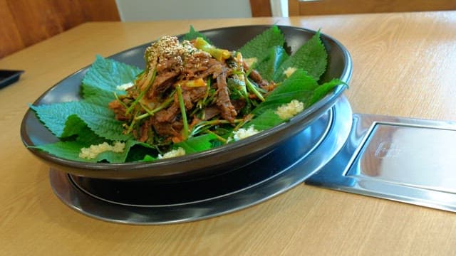 Spicy seasoned meat with perilla leaves on a plate on a wooden table