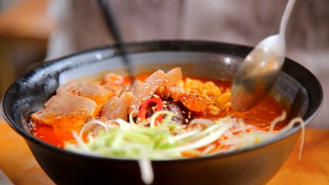 Spicy dombe meat ramen with toppings being stirred