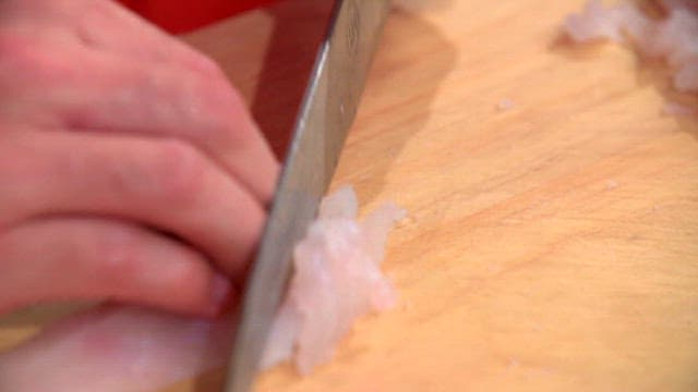 Slicing trimmed flatfish on a wooden cutting board