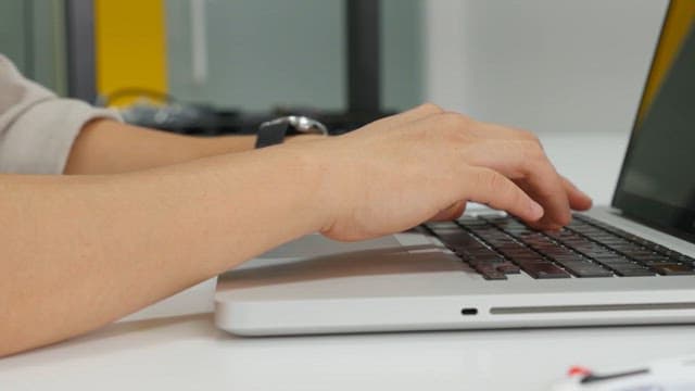Close-up of hands typing on a laptop