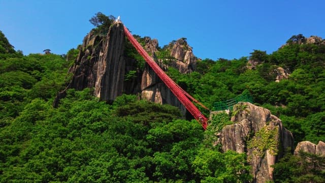 Red stairs and observation deck on a mountain covered with green trees