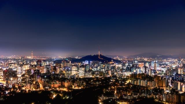 Panoramic view of a city skyline transitioning from night to early morning