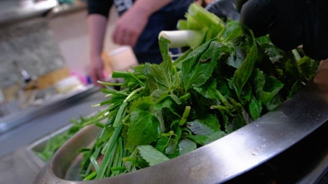 Preparation process of a dish with fresh green vegetables in a kitchen