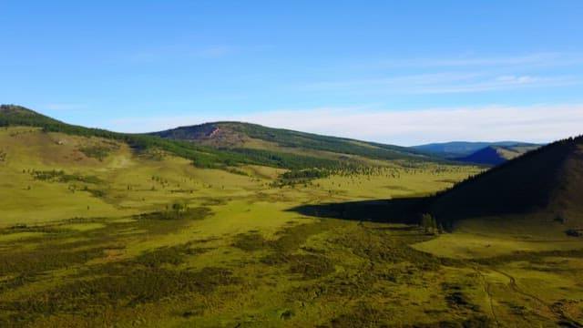 Wide green space surrounded by mountains