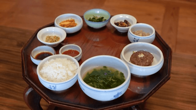 Traditional Wooden Table being Set with Korean Meal