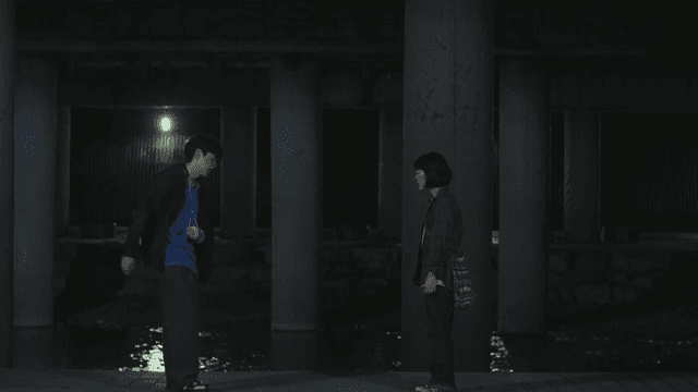 Two people having a conversation under a bridge at night