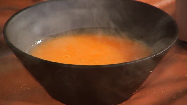 Adding sweet red bean paste to steaming carrot porridge
