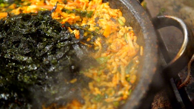 Stir frying bibimbap with fresh vegetables on a hot plate