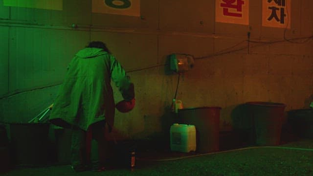 Person pouring water into bucket on dark street