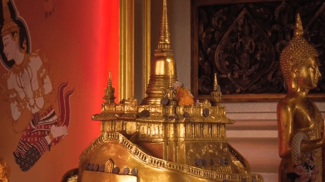 Golden stupa model in a temple with flower garlands
