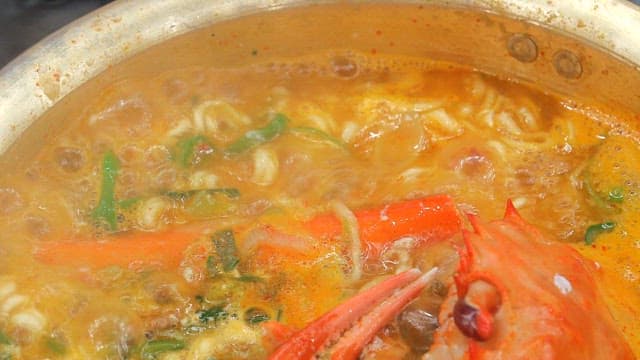Appetizing seafood ramen with red crab boiling in a pot