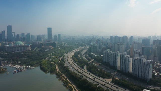Busy Traffic in a Riverside City with Dense Apartments and Buildings