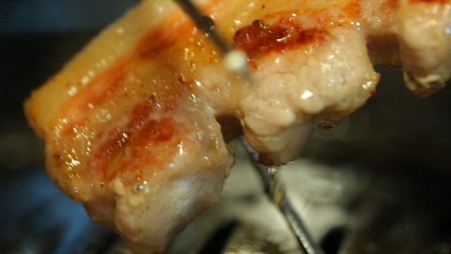 Grilled pork belly being cut with scissors