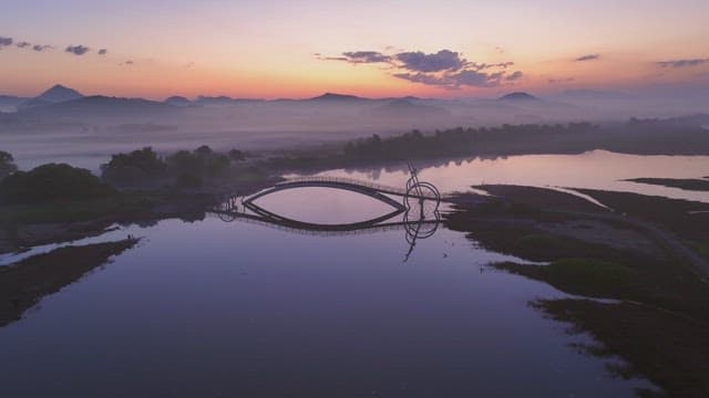 Serene river with misty mountain at sunset