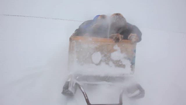 Man Riding Sled Through Blizzard