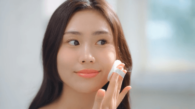 Woman applying makeup in a bright room