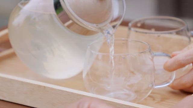 Pouring lemon tea into a glass on a tray