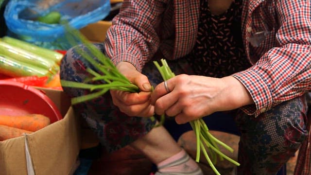 Person preparing fresh vegetables with a knife at a market