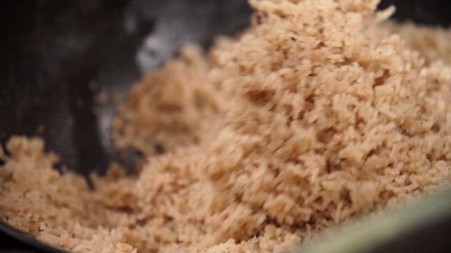 Stir-frying minced meat and noodles in a pan with a wooden spatula