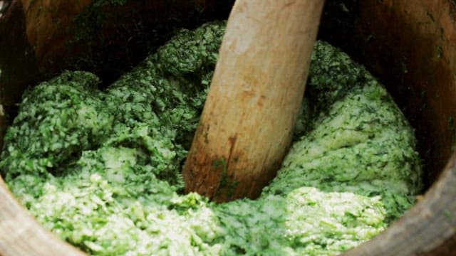 Green beeswax cake pounded in a wooden mortar