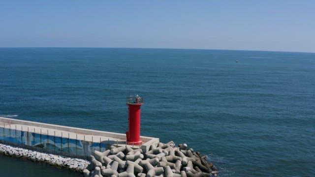 Red Lighthouseand Breakwater on a Tranquil Sea Coast