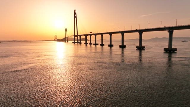 Sunset over a long bridge spanning the sea