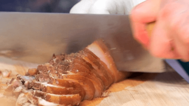Slicing boiled pork slices on a wooden cutting board