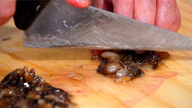 Slicing fresh sea urchin on a wooden cutting board