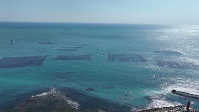 Blue sea with fish farm and coastal village