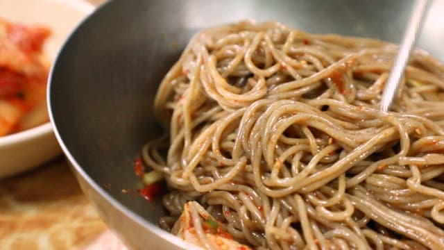 Mixing bibim naengmyeon with chopsticks