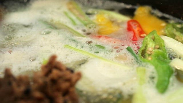 Adding soybean paste to a broth with various vegetables boiling