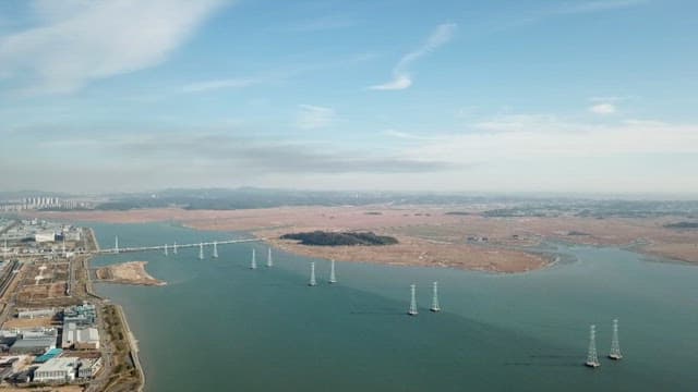 Waterfront area with waterways and transmission towers under a bright blue sky