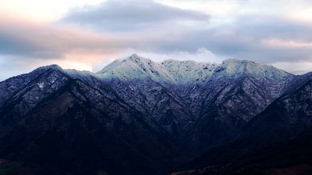 Snow-covered mountains under cloudy skies