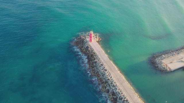 Red lighthouse on a long seawall by the sea
