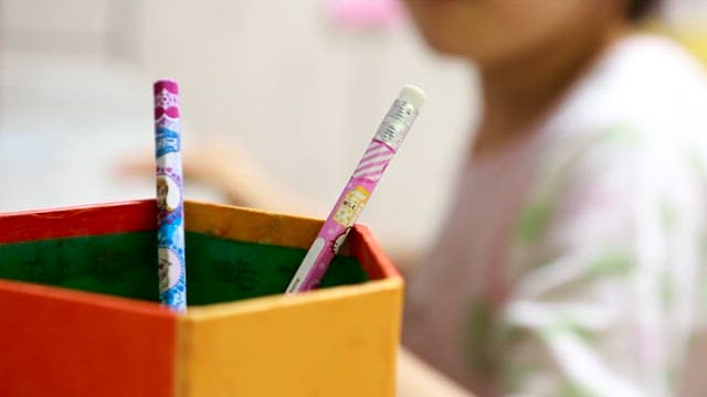 Child Taking a Pencil out of a Pen Stand