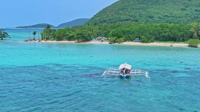 Bangka boat sailing near lush green tropical islands