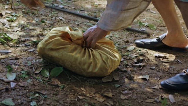 Old Man Taking Out Valuables from a Cloth Hidden in the Forest