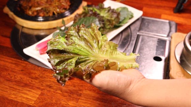 Prepare the wrap by placing the stir-fried pork on top of fresh lettuce.