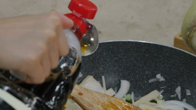 Adding soy sauce to the skillet with the chopped onions