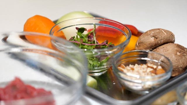 Fresh vegetables and rice cakes in a glass bowl on the kitchen counter