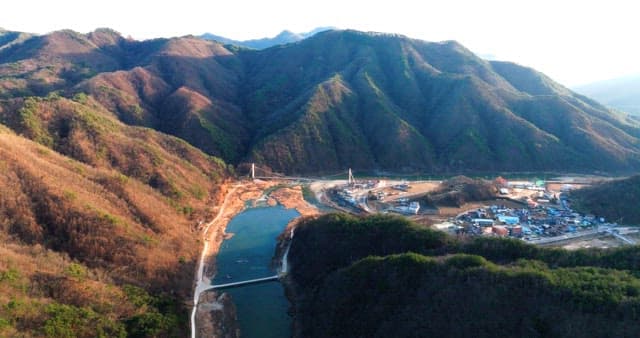 Mountain Village by the River with Suspension Bridge
